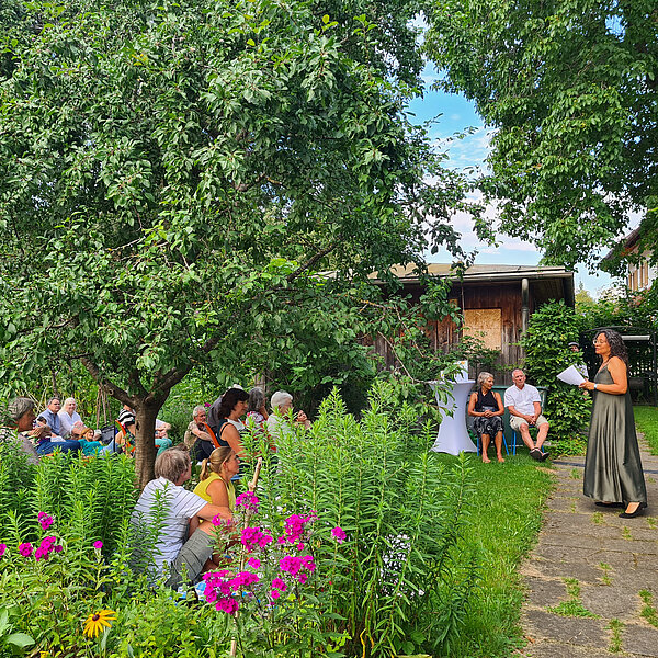 Menschen im Garten lauschen einer Sängerin